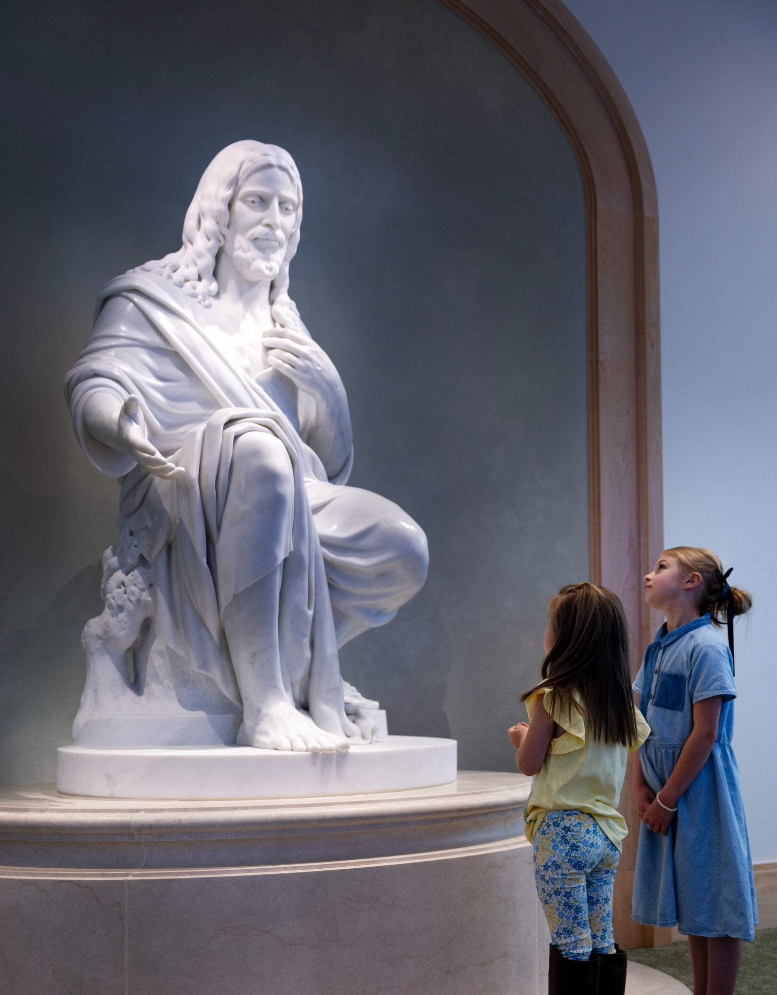 Children visit the “Come Unto Me” statue in the Temple Square Visitors’ Center. The statue by Swiss artist Christian Bolt sits at the center point of the lower level. It is carved from Carrara marble and depicts the Savior of the world extending an invitation of peace and compassion.