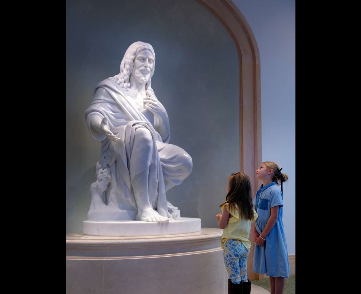 Children visit the “Come Unto Me” statue in the Temple Square Visitors’ Center. The statue by Swiss artist Christian Bolt sits at the center point of the lower level. It is carved from Carrara marble and depicts the Savior of the world extending an invitation of peace and compassion.