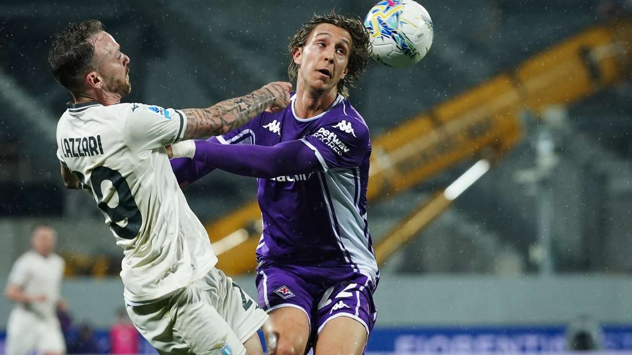 Lazio's Manuel Lazzari, left, fights for the ball with Fiorentina's Jacopo Fazzini during the Serie A soccer match between Fiorentina and Lazio in Florence, Italy, Monday, April 13, 2026.