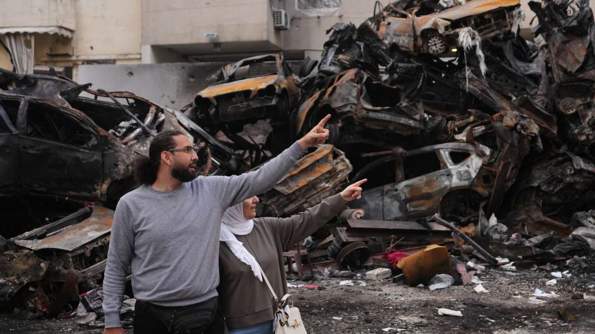 Residents gesture and point toward damage as they stand near charred cars at the site of a building destroyed in an Israeli airstrike last Wednesday in central Beirut, Lebanon, Tuesday.