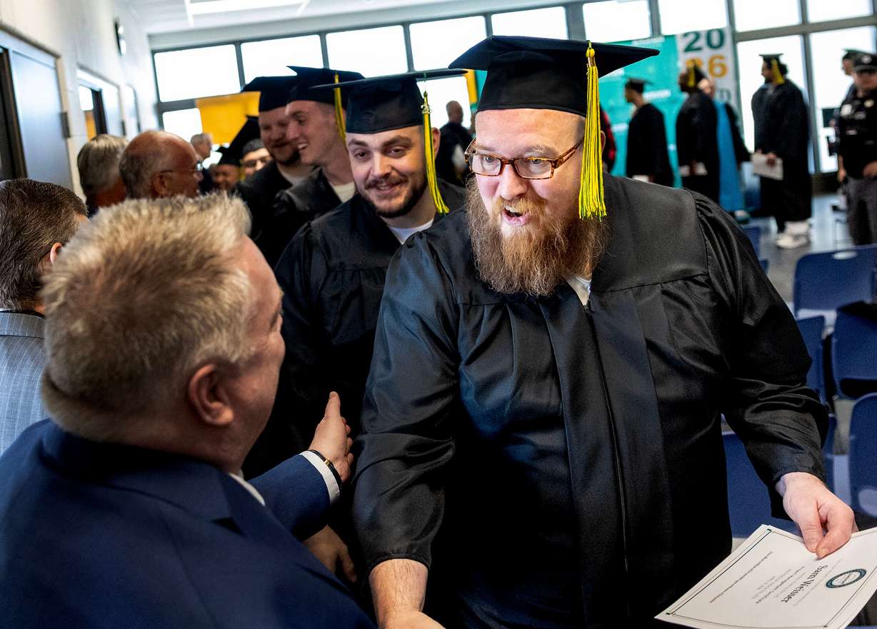 Sam, right, is congratulated by one of his adjunct professors, Mark Elkins, after receiving a graduation certificate from the Ensign College Prison Education Program at the Utah State Correctional Facility in Salt Lake City on Wednesday. The ceremony was the first held off-campus in school history.