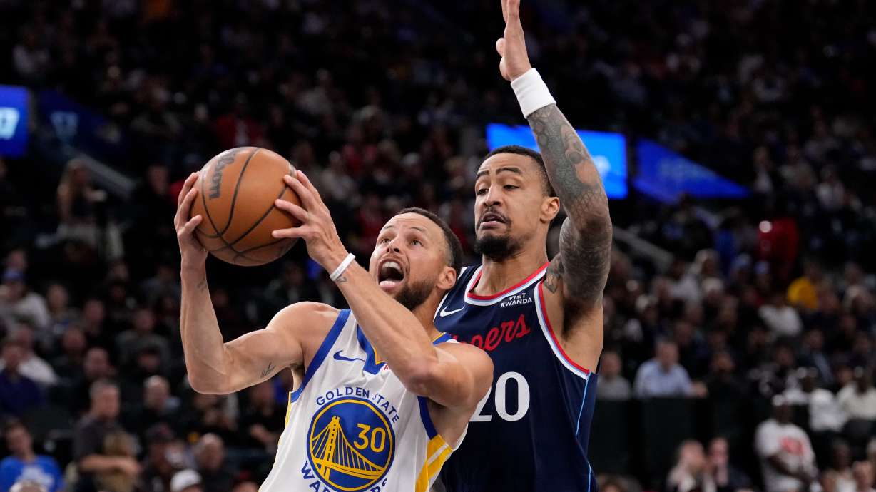 Golden State Warriors guard Stephen Curry, left, shoots as LA Clippers forward John Collins defends during the first half of an NBA play-in tournament basketball game Wednesday, April 15, 2026, in Inglewood, Calif.