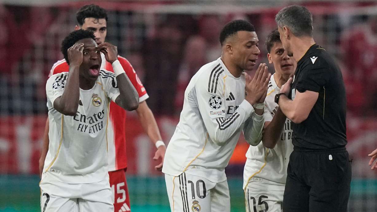 Real Madrid's Kylian Mbappe, center, and Vinicius Jr., left, disagree with referee Slavko Vincic during the Champions League quarterfinal second leg soccer match between Bayern Munich and Real Madrid in Munich, Germany, Wednesday, April 15, 2026.