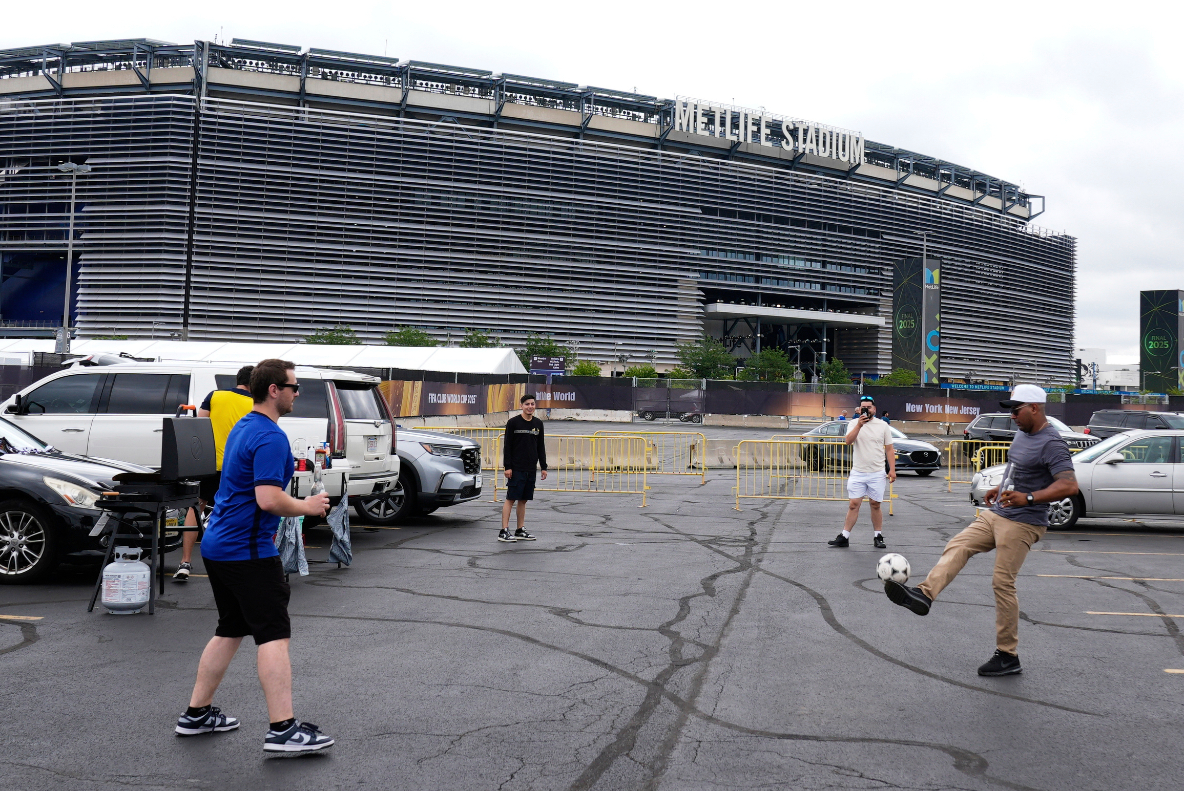FILE - Fans play with a ball outside the Metlife Stadium prior to the Club World Cup final soccer match between Chelsea and PSG in East Rutherford, N.J., Sunday, July 13, 2025. 