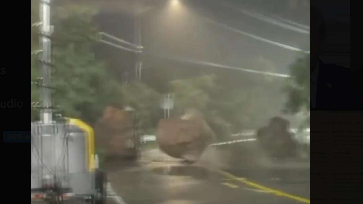 In this still image from video provided by the Hawaii Department of Transportation, a massive boulder tumbles onto Kamehameha Highway in Waimea Bay, April 10. The highway segment was later closed for repairs and boulder removal.