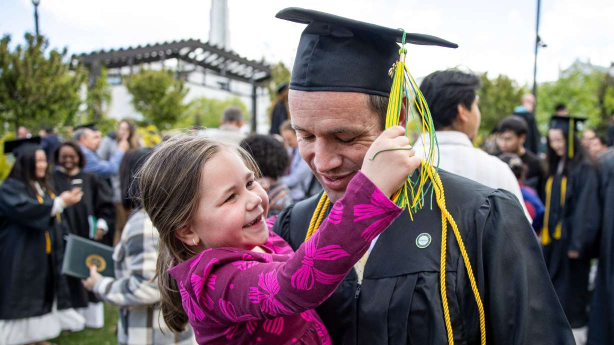 Corey Liddiard as his daughter plays with his tassel after the 139th Ensign College Commencement Exercises at the Salt Lake Tabernacle on Temple Square in Salt Lake City on Friday. Liddiard is part of the school's largest ever graduating class.