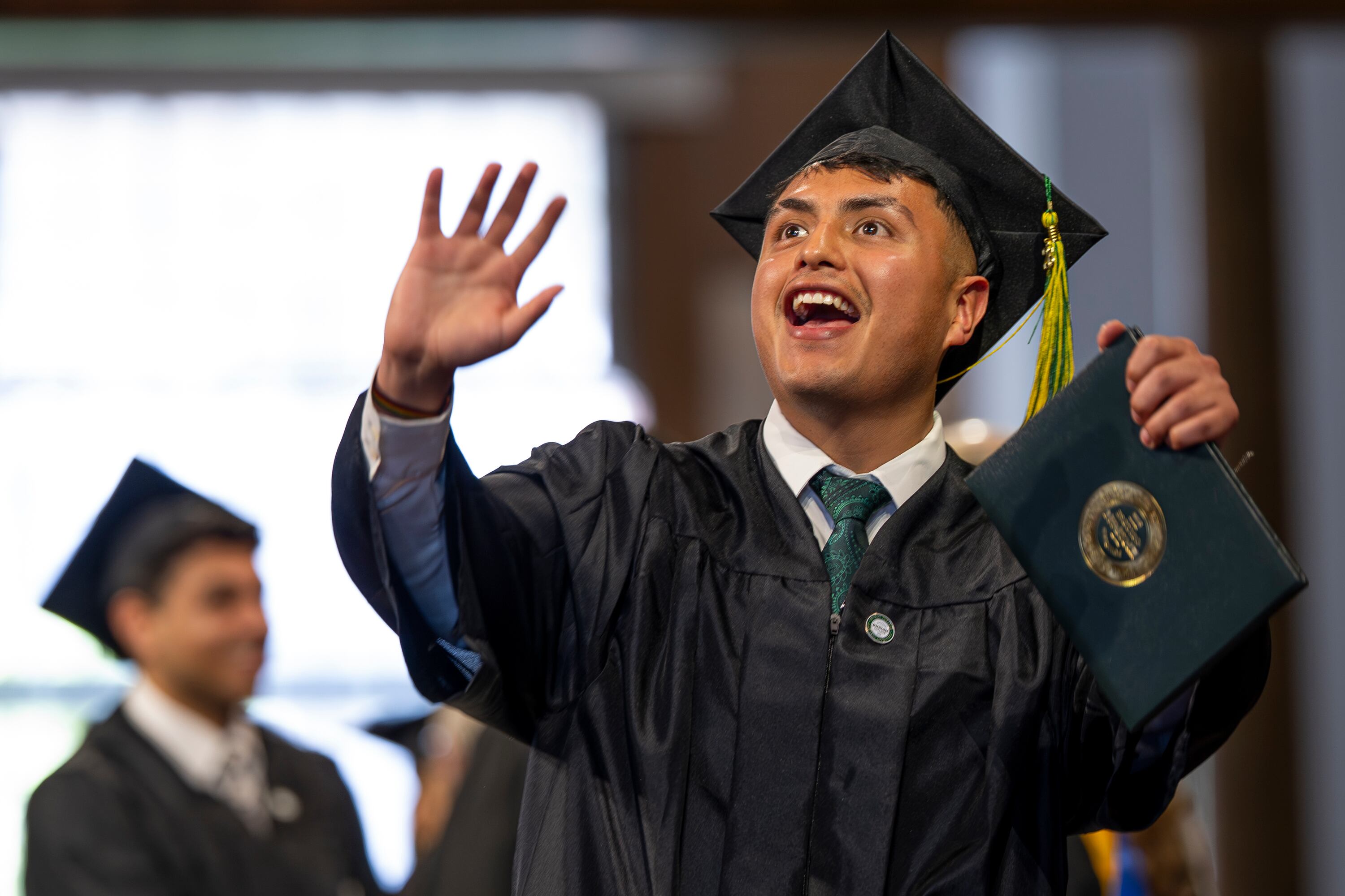 A graduate waves to family as they cross the stage after receiving their diploma during the 139th Ensign College commencement exercises at the Salt Lake Tabernacle on Temple Square in Salt Lake City on Friday. The class was the largest in school history.