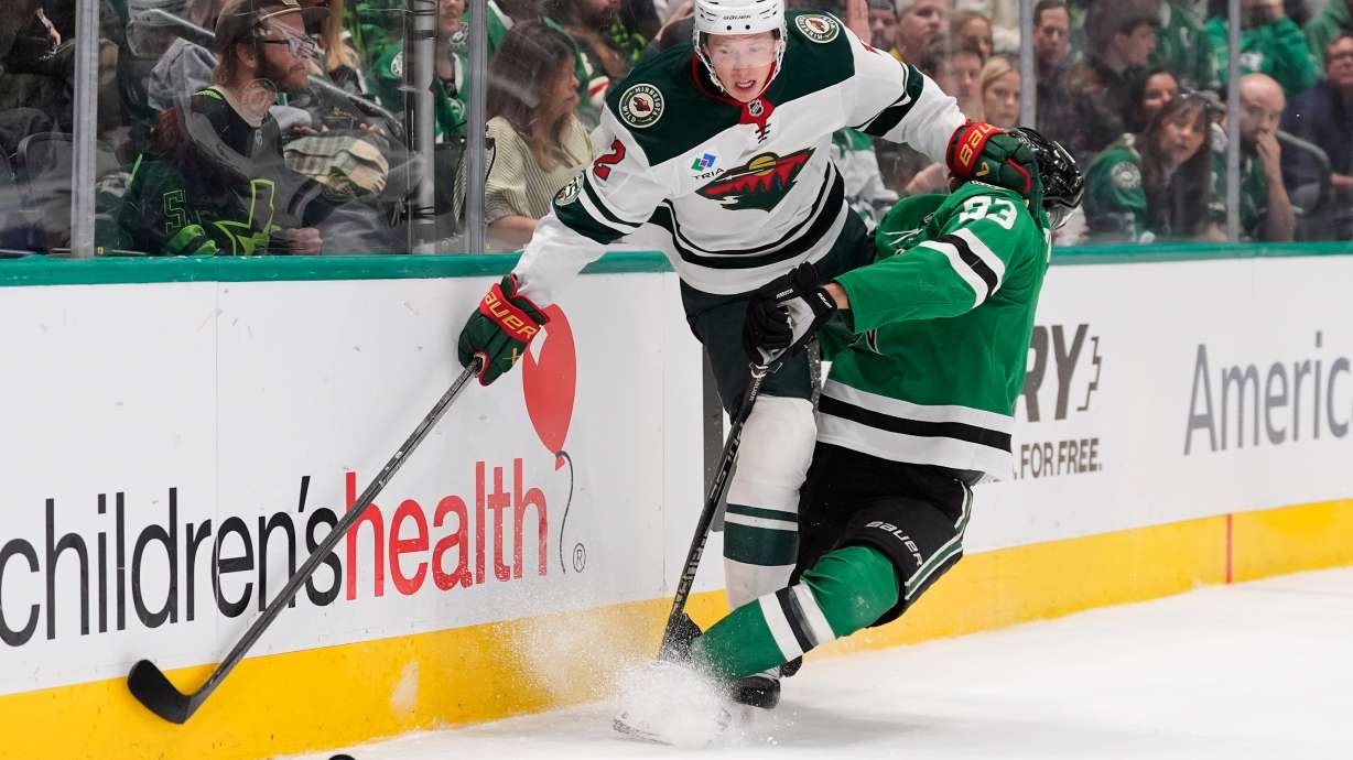 Minnesota Wild left wing Matt Boldy (12) and Dallas Stars center Wyatt Johnston (53) slam into the boards chasing after the puck in the first period of an NHL hockey game Thursday, April 9, 2026, in Arlington, Texas.