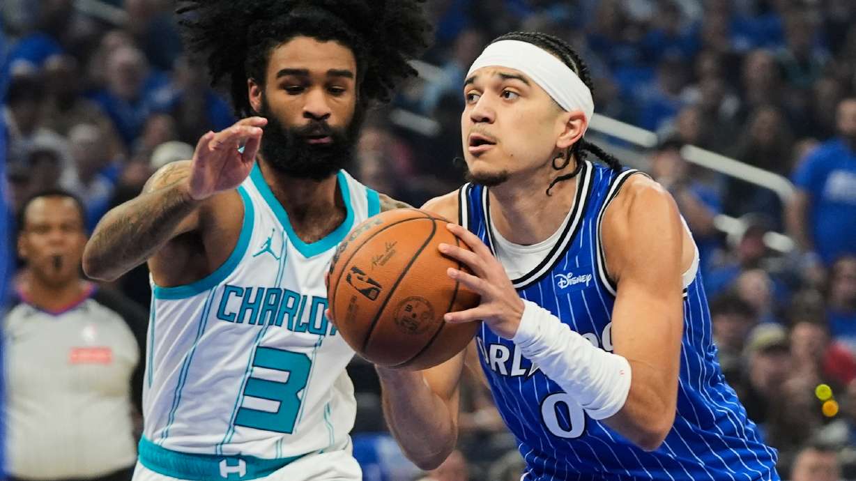 Orlando Magic guard Anthony Black (0) drives around Charlotte Hornets guard Coby White (3) during the first half of an NBA play-in tournament basketball game, Friday, April 17, 2026, in Orlando, Fla.