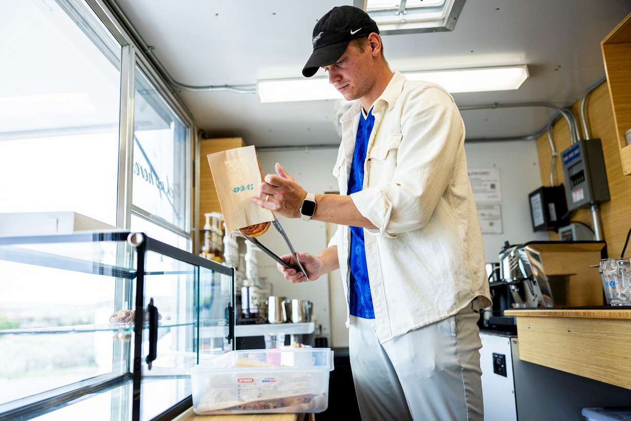 Alfred Kilis, co-owner of SVEA Scandinavian Kafé on Wheels, bags a cinnamon bun for a customer at his food truck in Eagle Mountain on April 10.