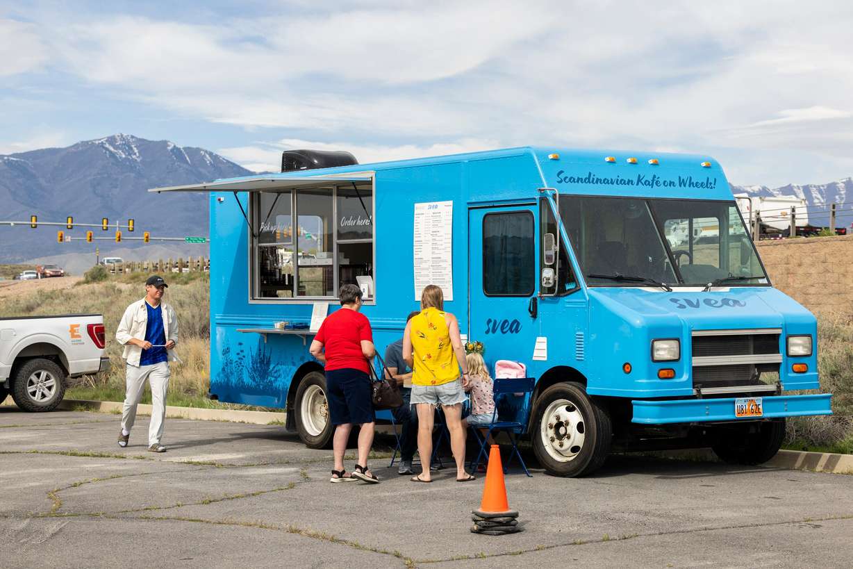 Alfred Kilis, co-owner of SVEA Scandinavian Kafé on Wheels, brings straws to customers at his food truck in Eagle Mountain on April 10.