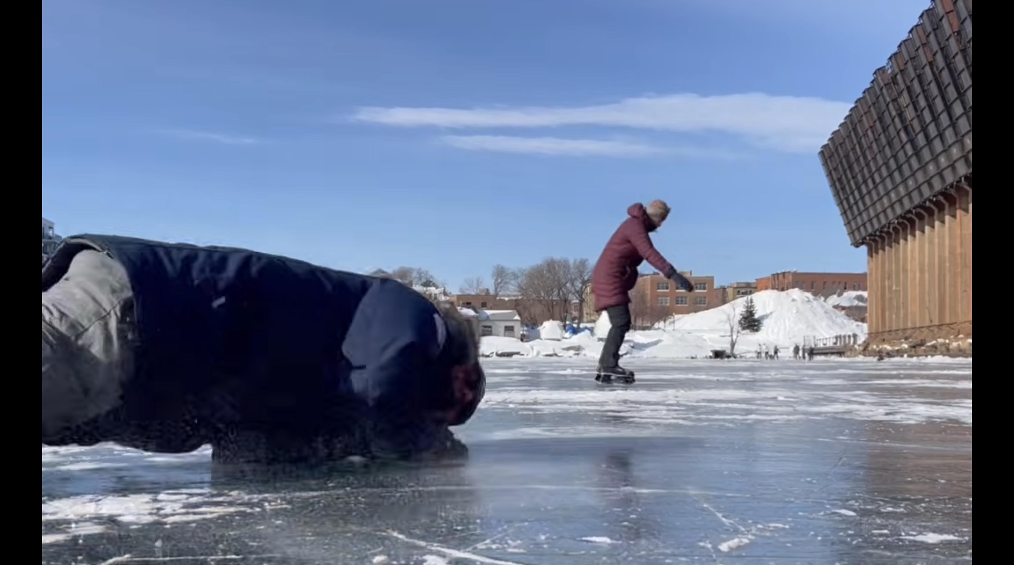 Jamie Dolan skates on the frozen Lake Superior while her friend, Steve, slides across the ice after falling.