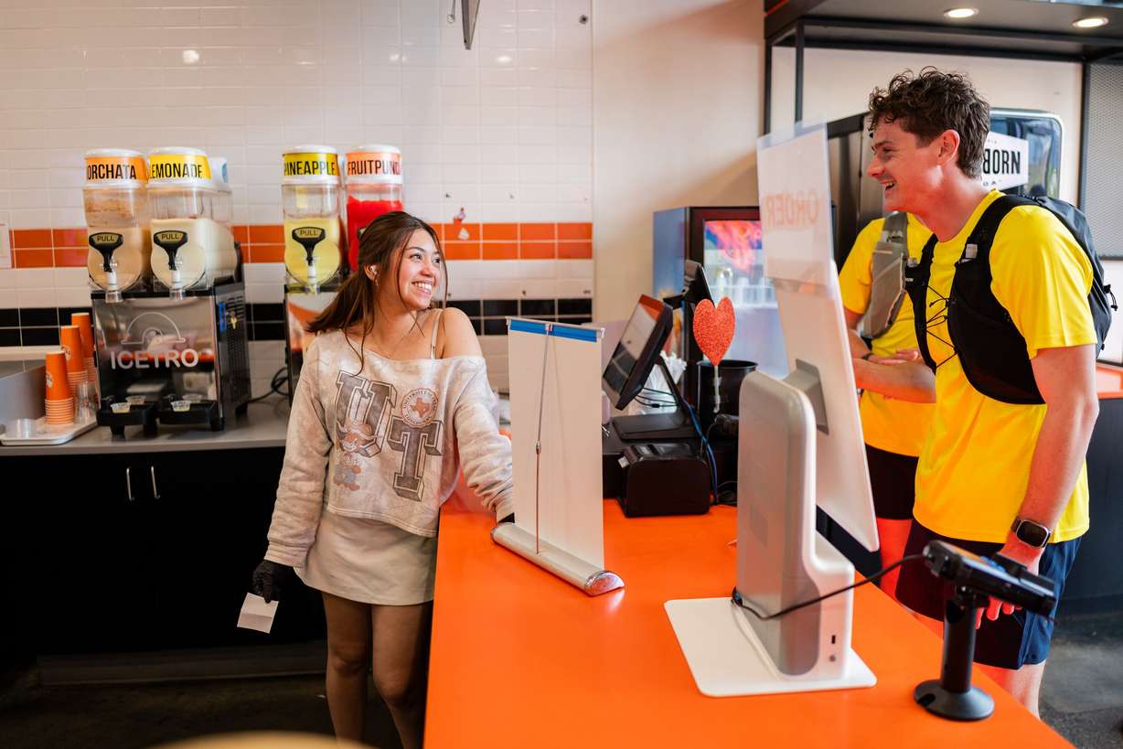 Joseph Carwin, right, orders from Ivy Silva, left, at Two Hands Seoul Fresh Corndogs while attempting to set a Guinness World Record for fast-food eating in a 24-hour period with seven of his friends in Sandy on April 11.