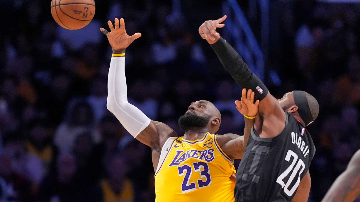 Los Angeles Lakers forward LeBron James, left, takes a pass as Houston Rockets guard Josh Okogie defends during the first half in Game 1 of a first-round NBA playoffs basketball series Saturday, April 18, 2026, in Los Angeles.