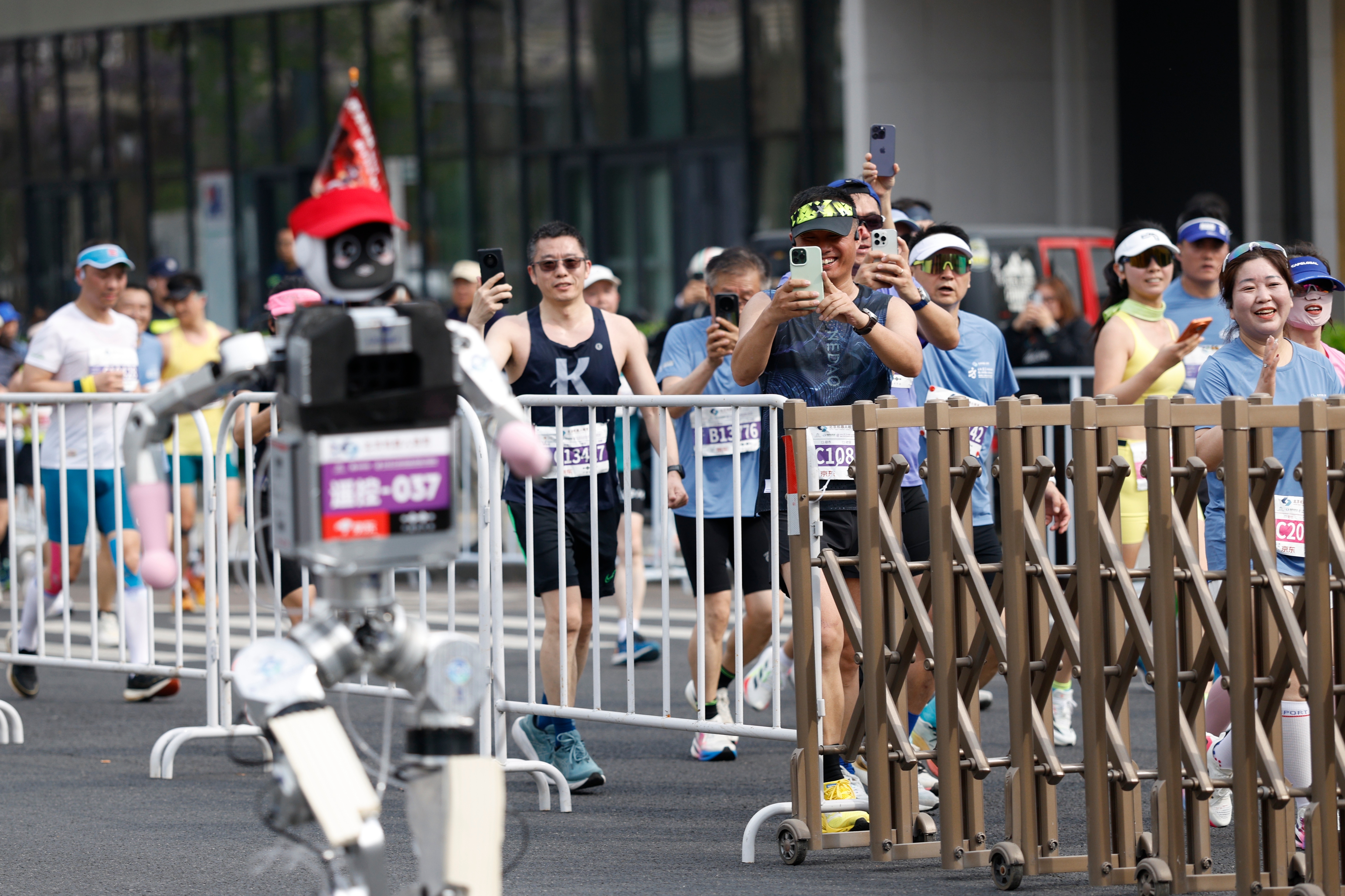 Runners take pictures of a humanoid robot in the second Beijing E-Town Half Marathon and Humanoid Robot Half Marathon in Beijing Sunday, April 19, 2026. 