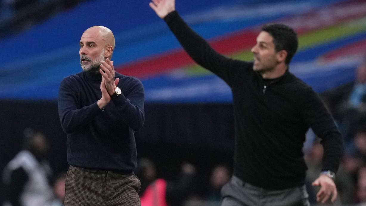 Manchester City's head coach Pep Guardiola, left encourages his players as Arsenal's manager Mikel Arteta gestures to his during the English League Cup final soccer match between Arsenal and Manchester City in London, Sunday, March 22, 2026.