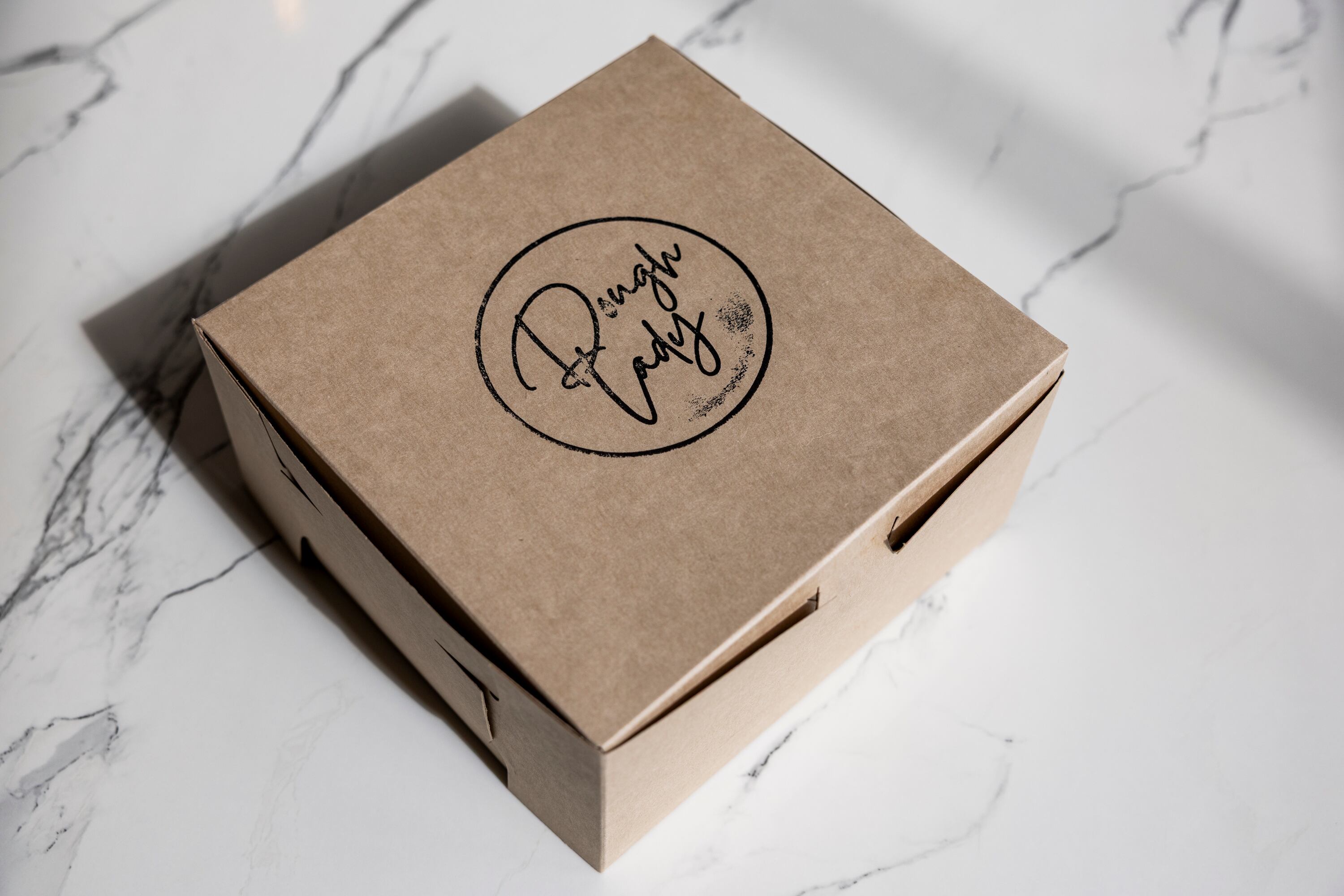 A box with Dough Lady cinnamon rolls sits on a table at Dough Lady in Millcreek on Thursday, April 9, 2026.