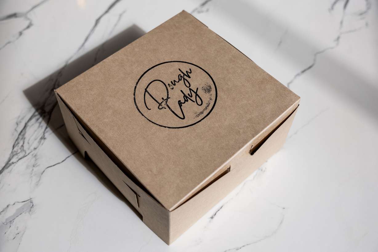 A box with Dough Lady cinnamon rolls sits on a table at Dough Lady in Millcreek on Thursday, April 9, 2026.