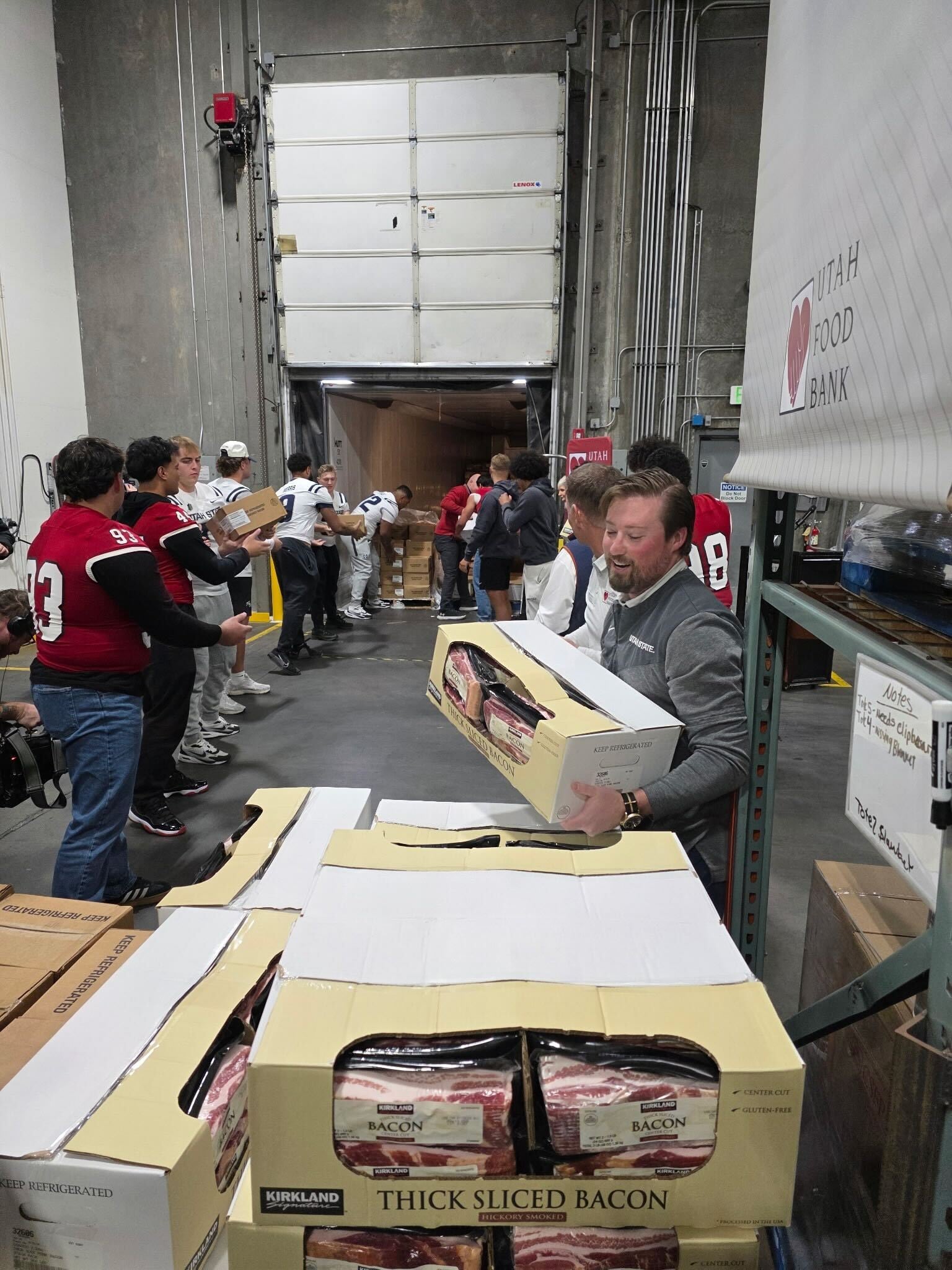 Football players from Utah State University, Brigham Young University and Southern Utah University worked together to pass boxes along an assembly line in the Utah Food Bank warehouse in South Salt Lake, Friday.