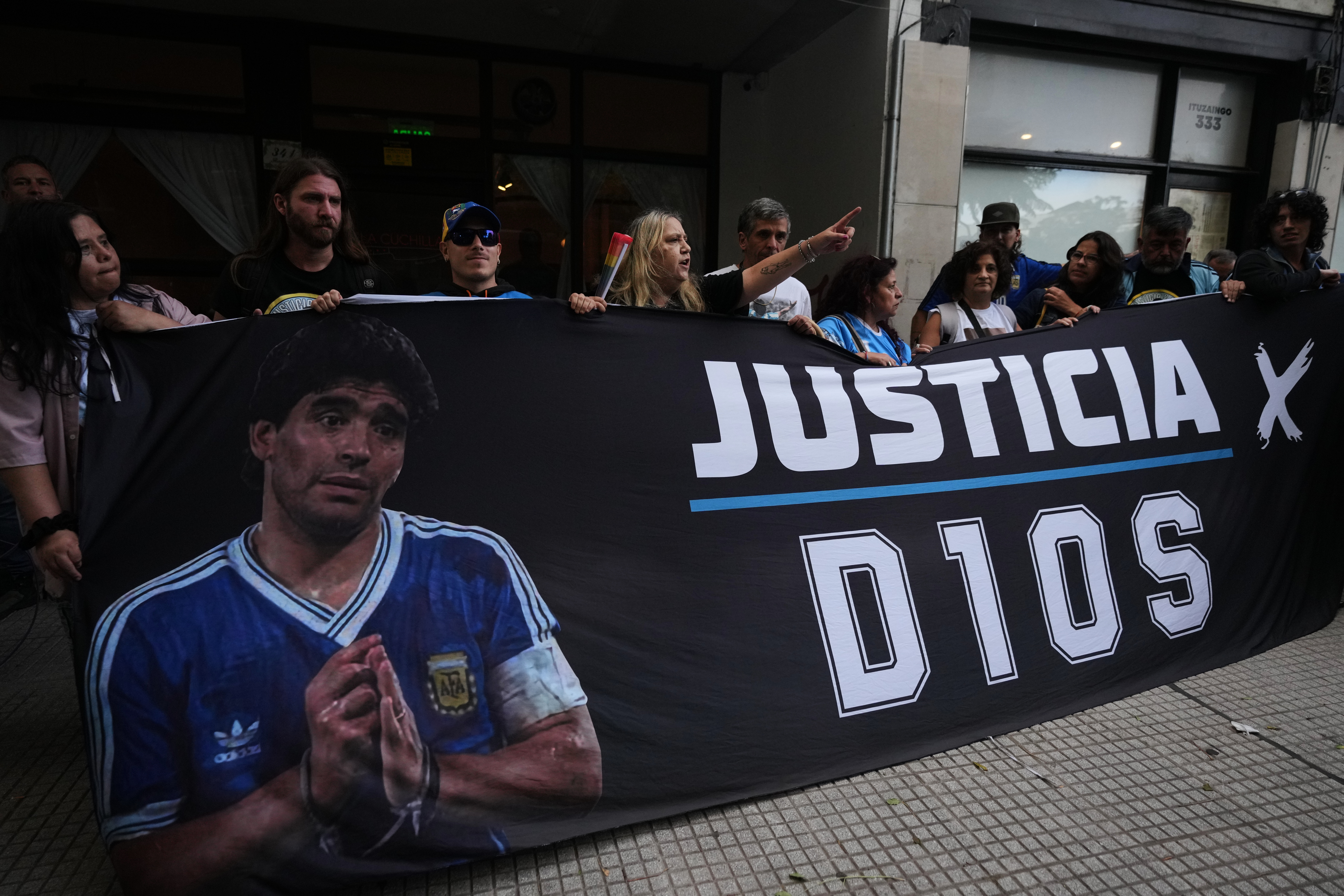 Fans of the late soccer star Diego Maradona stand outside court on the first day of the trial of his medical team for alleged homicide by negligence in San Isidro, Argentina, Tuesday, April 14, 2026. 