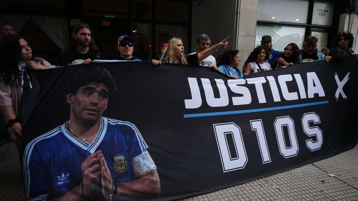 Fans of the late soccer star Diego Maradona stand outside court on the first day of the trial of his medical team for alleged homicide by negligence in San Isidro, Argentina, Tuesday, April 14, 2026.