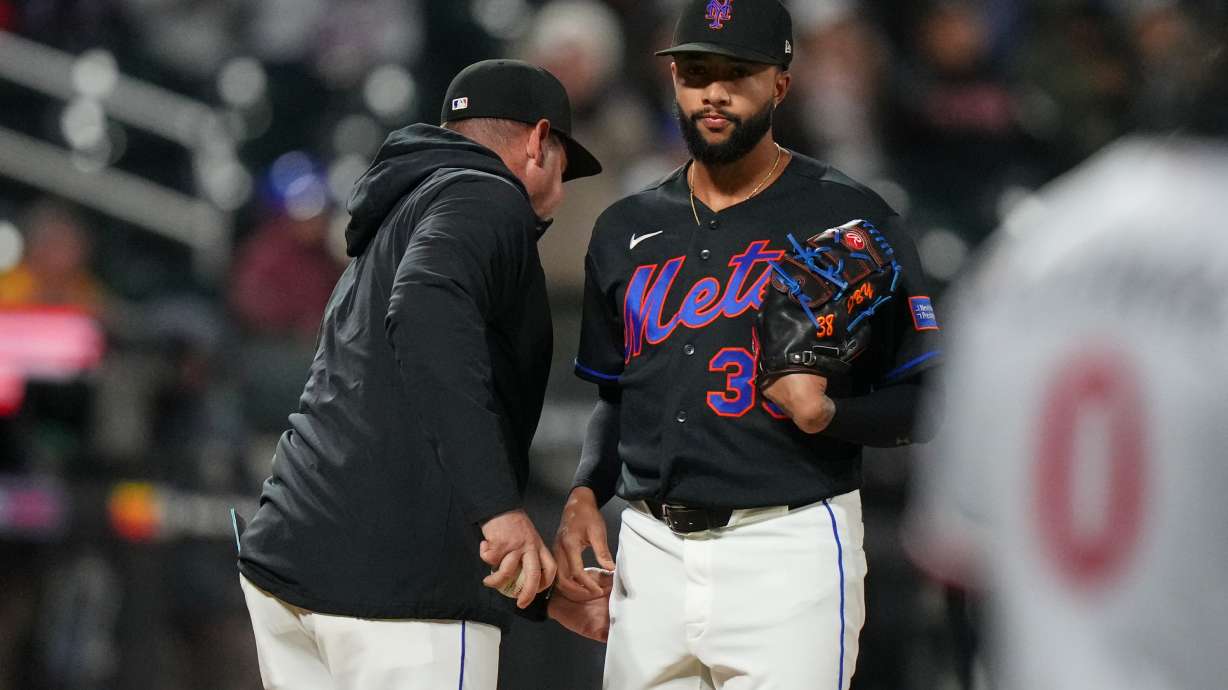 New York Mets pitcher Devin Williams, right, hands the ball to manager Carlos Mendoza as he leaves during the ninth inning of a baseball game against the Minnesota Twins Tuesday, April 21, 2026, in New York.