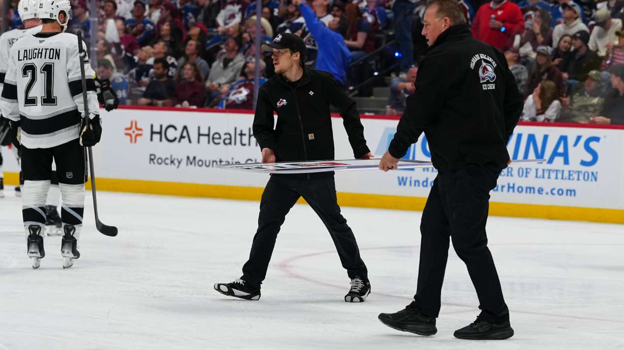 Members of the Colorado Avalanche conversion crew carry a new piece of glass to the Los Angeles Kings' bench during the second period of Game 2 in the first round of the NHL hockey Stanley Cup playoffs against the Colorado Avalanche, Tuesday, April 21, 2026, in Denver.