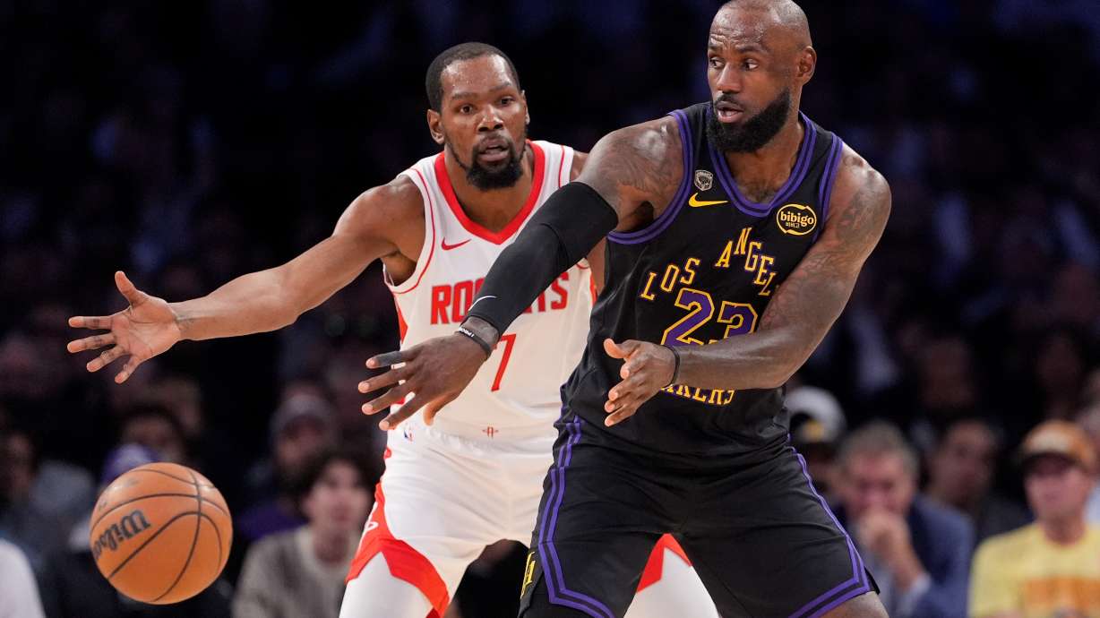 Los Angeles Lakers forward LeBron James, right, passes the ball while under pressure from Houston Rockets forward Kevin Durant during the first half in Game 2 of a first-round NBA playoffs basketball series Tuesday, April 21, 2026, in Los Angeles.