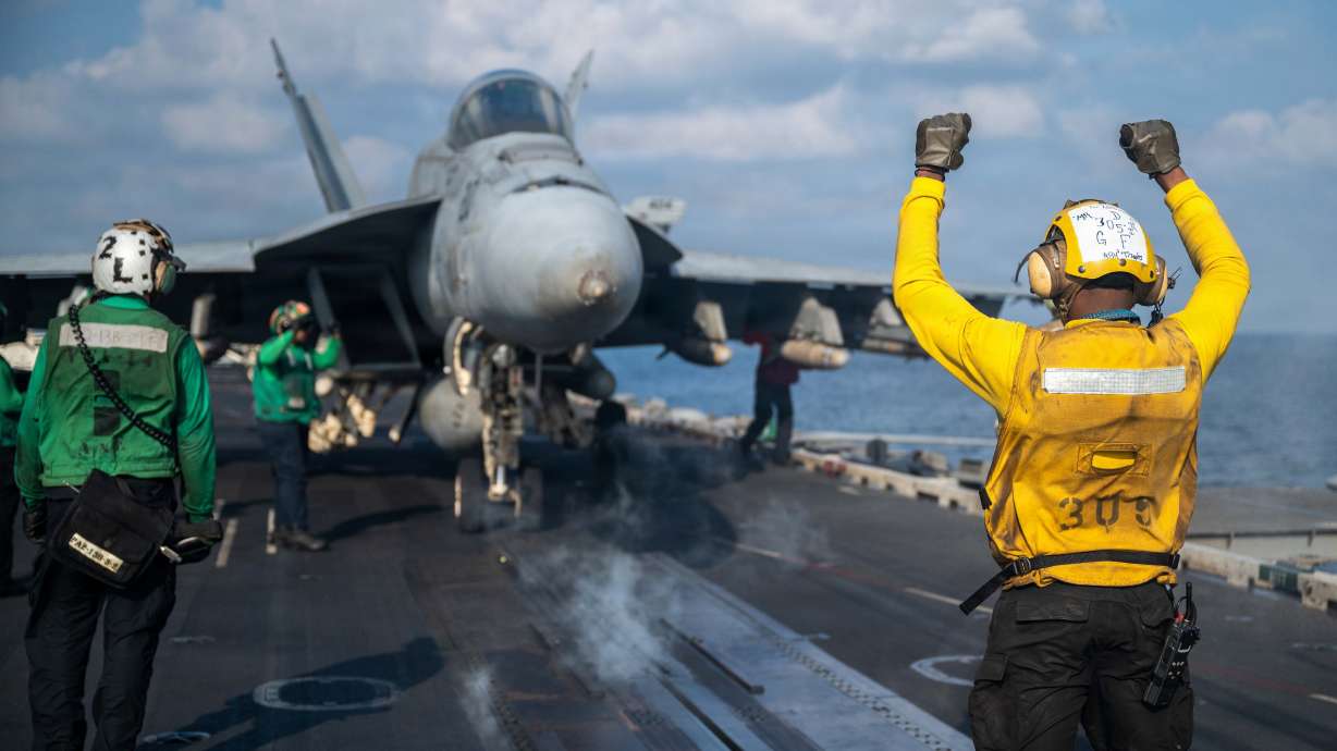 A sailor signals an F/A-18E Super Hornet on the flight deck of USS Abraham Lincoln in support of Operation Epic Fury, March 4. Military leaders say defense against electronic communication propaganda must be taken during the Iran war.