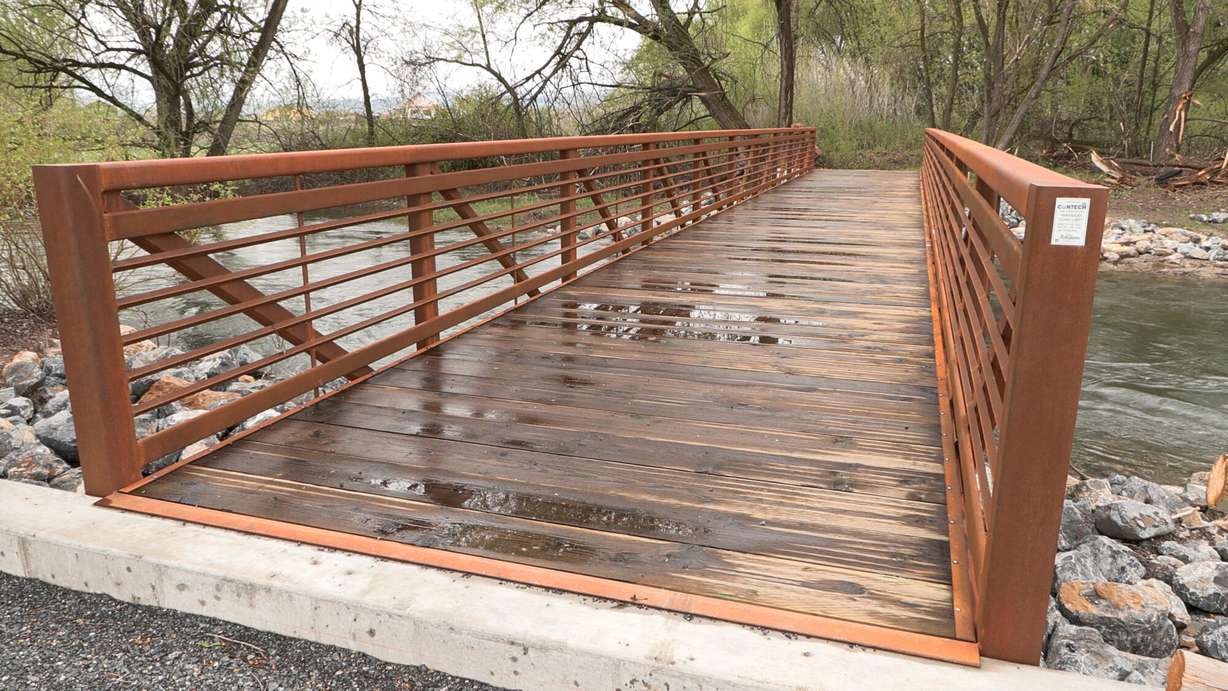 A large pedestrian bridge extends walking trails through Trapper Park, as part of a restoration project along the Logan River, Wednesday. About 60 cars and other debris have been removed from the river so far.