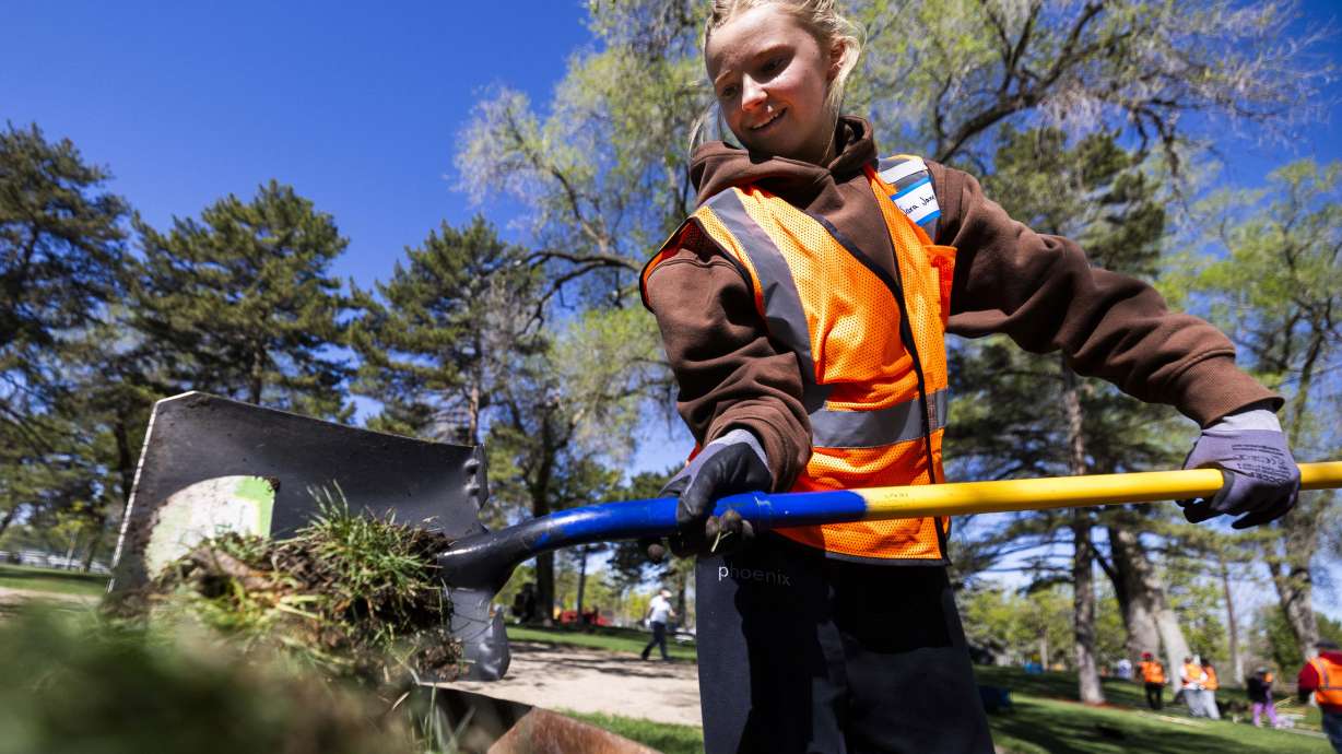 Sara Jane Giles, a senior at Farmington High School, puts dug up grass into a wheelbarrow while volunteering at a Salt Lake City Department of Public Lands Earth Day event at Jordan Park in Salt Lake City on Sunday.