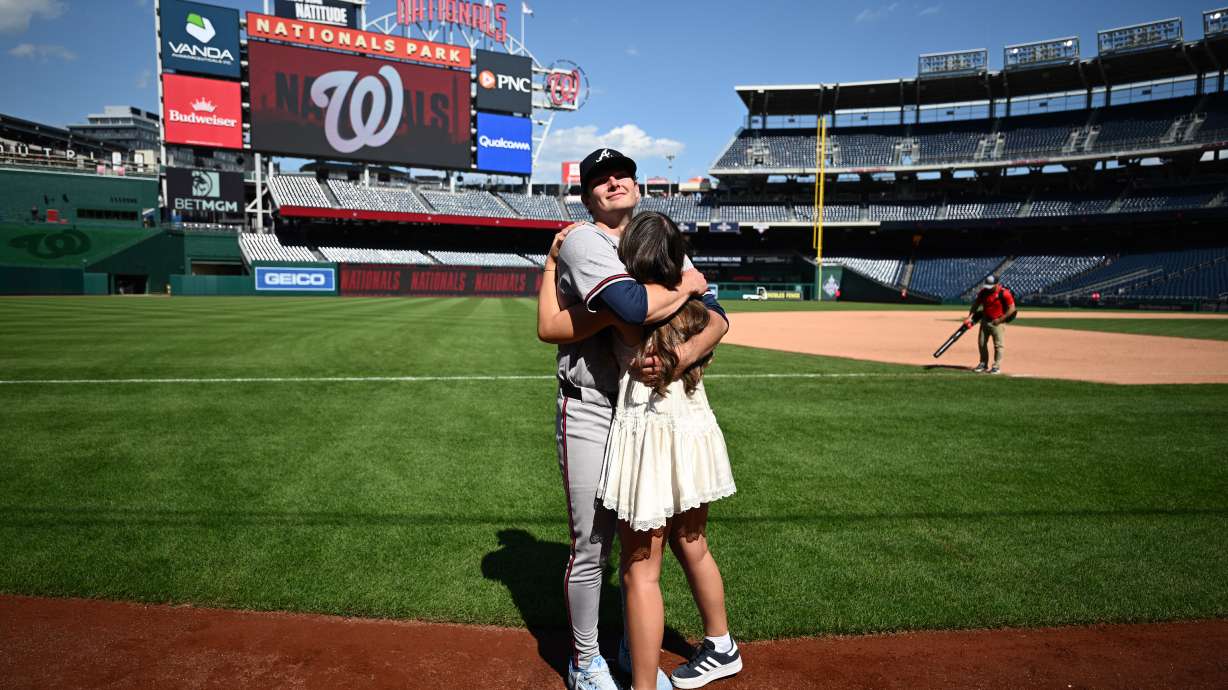 Atlanta Braves starting pitcher JR Ritchie, back, hugs his fiancée Makena Miller after winning his major league debut baseball game against the Washington Nationals, Thursday, April 23, 2026, in Washington.