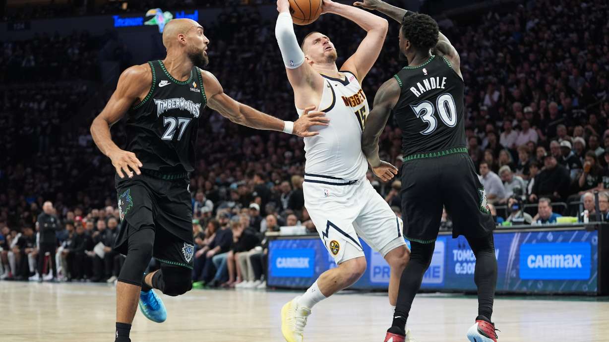Denver Nuggets center Nikola Jokic (15) works toward the basket as Minnesota Timberwolves center Rudy Gobert (27) and forward Julius Randle (30) defend during the first half in Game 3 of a first-round NBA basketball playoff series, Thursday, April 23, 2026, in Minneapolis.