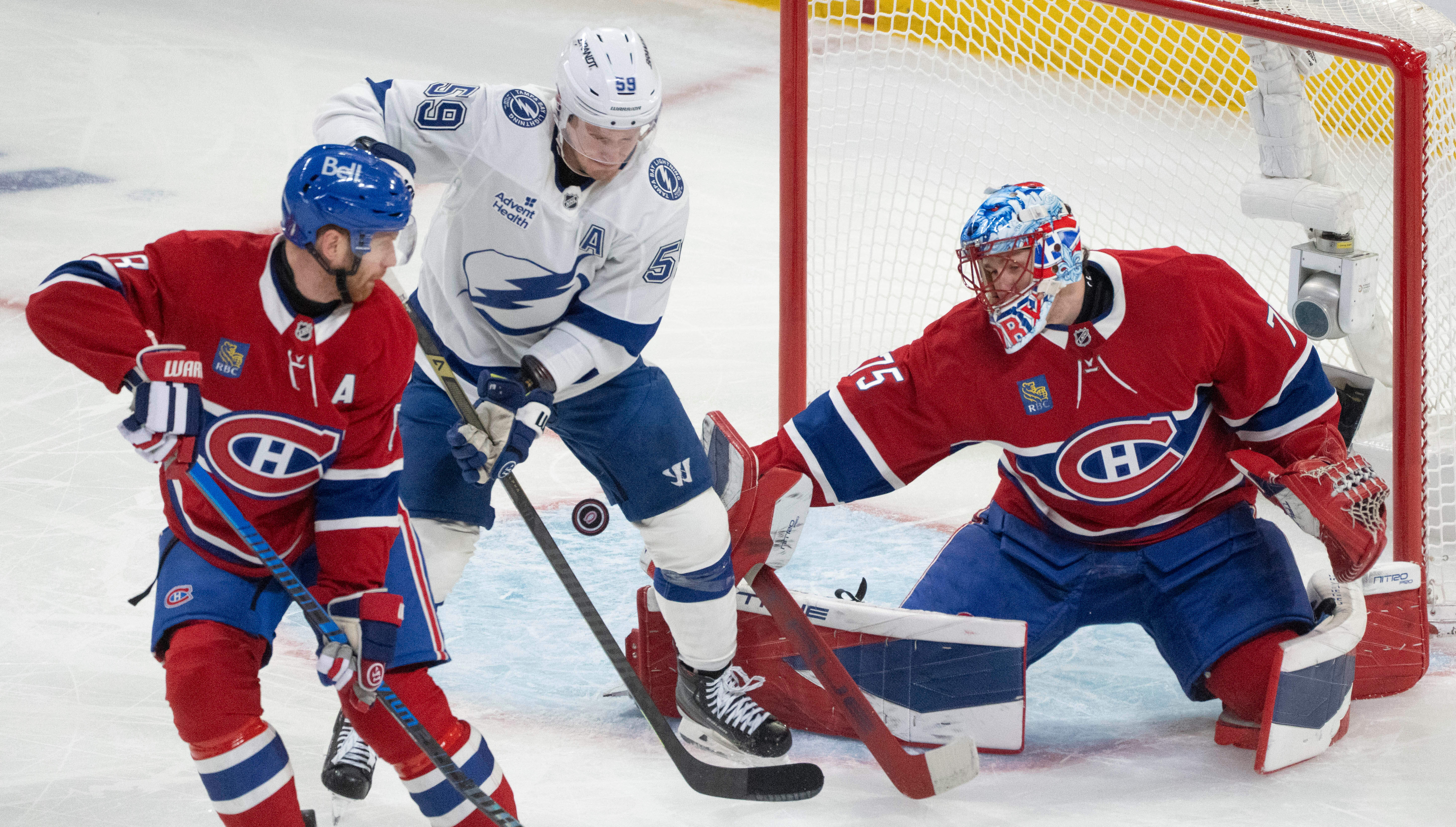 Montreal Canadiens goaltender Jakub Dobes (75) makes a save as Tampa Bay Lightning's Jake Guentzel (59) battles for the rebound against Canadiens' Mike Matheson (8) during the first period of Game 3 in a first-round NHL hockey Stanley Cup playoff series in Montreal, Friday, April 24, 2026. 