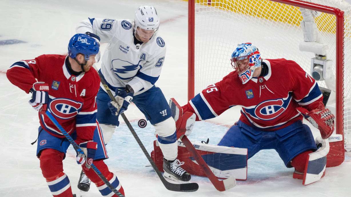 Montreal Canadiens goaltender Jakub Dobes (75) makes a save as Tampa Bay Lightning's Jake Guentzel (59) battles for the rebound against Canadiens' Mike Matheson (8) during the first period of Game 3 in a first-round NHL hockey Stanley Cup playoff series in Montreal, Friday, April 24, 2026.