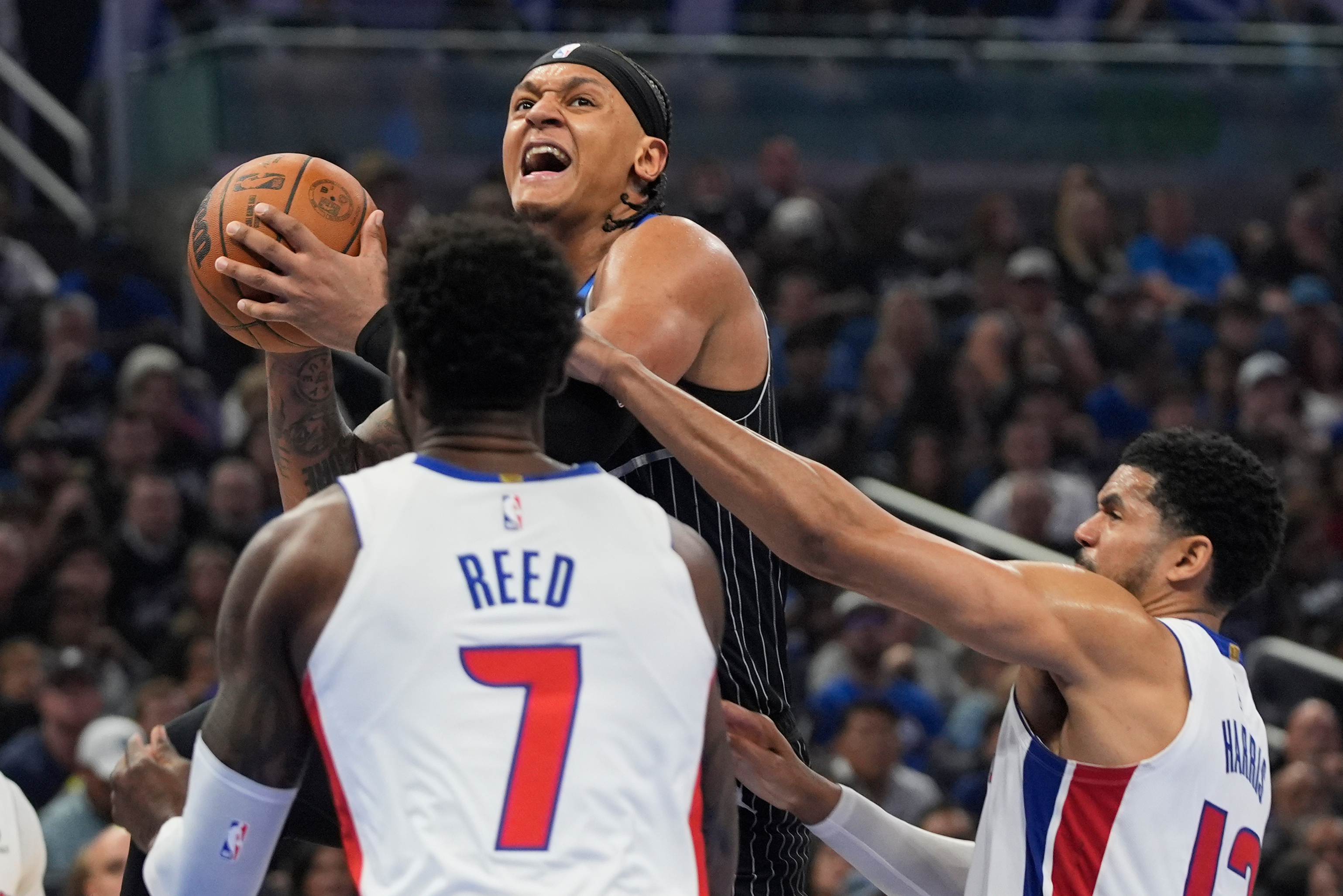 Orlando Magic forward Paolo Banchero, center, goes up for a shot over Detroit Pistons forward Paul Reed (7) and forward Tobias Harris, right, during the second half in Game 3 of a first-round NBA basketball playoff series, Saturday, April 25, 2026, in Orlando, Fla. 