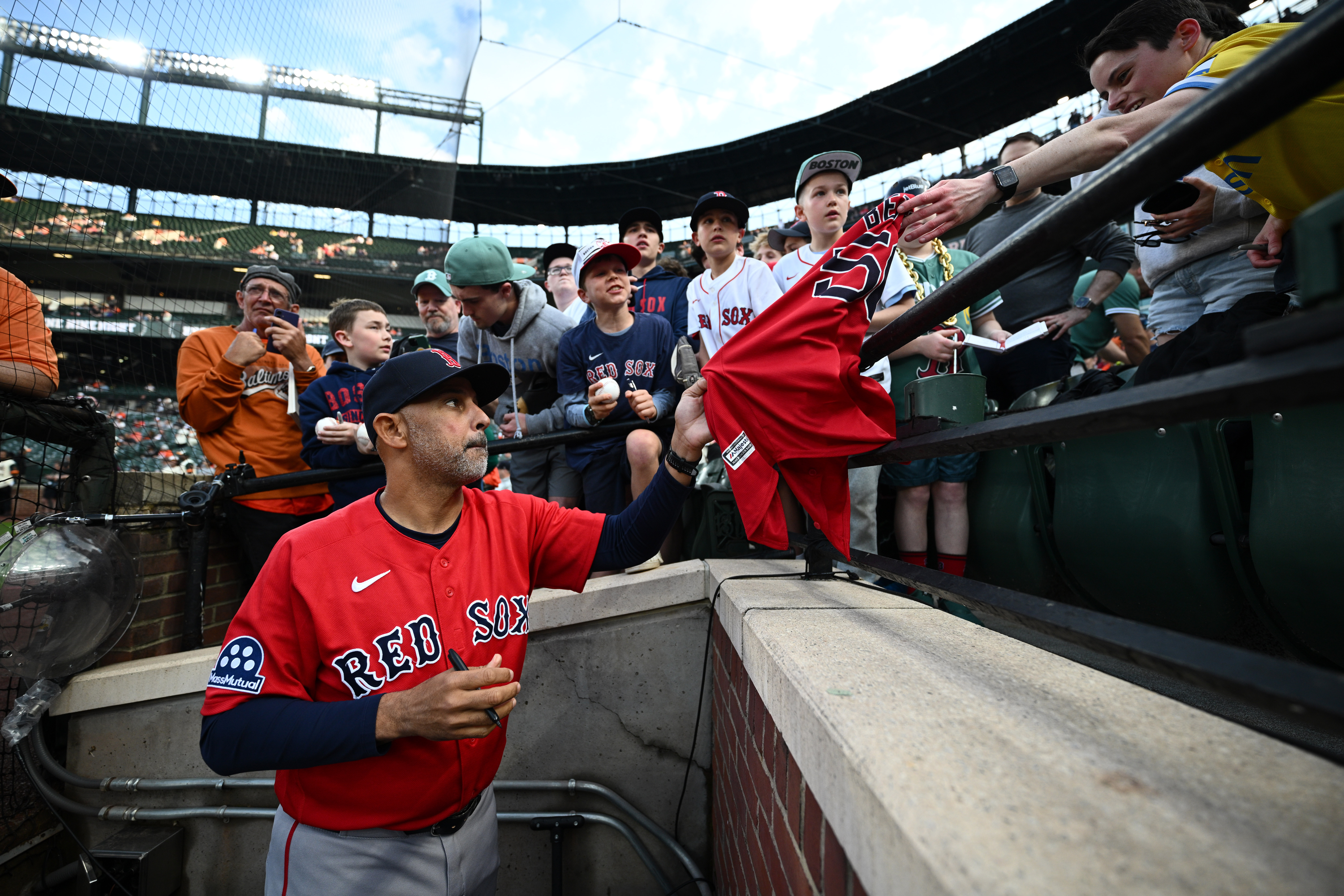 Boston Red Sox manager Alex Cora, foreground, gives autographs to fans before a baseball game against the Baltimore Orioles, Friday, April 24, 2026, in Baltimore. 