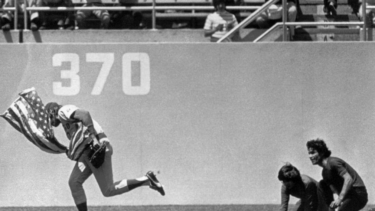 FILE - Outfielder Rick Monday of the Chicago Cubs dashes between two men in the Dodger Stadium Outfield in Los Angeles, in this April 25, 1976 photo, snatching an American flag the men were about to burn.