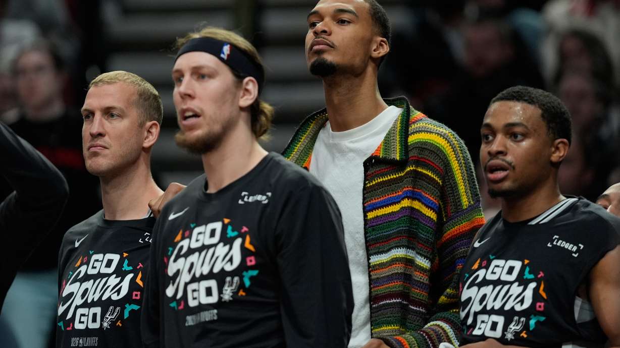 San Antonio Spurs forward Victor Wembanyama, center, wears street cloths on the bench as he sits out Game 3 of a first-round NBA playoffs basketball series against the Portland Trail Blazers in Portland, Ore, Friday, April 24, 2026.