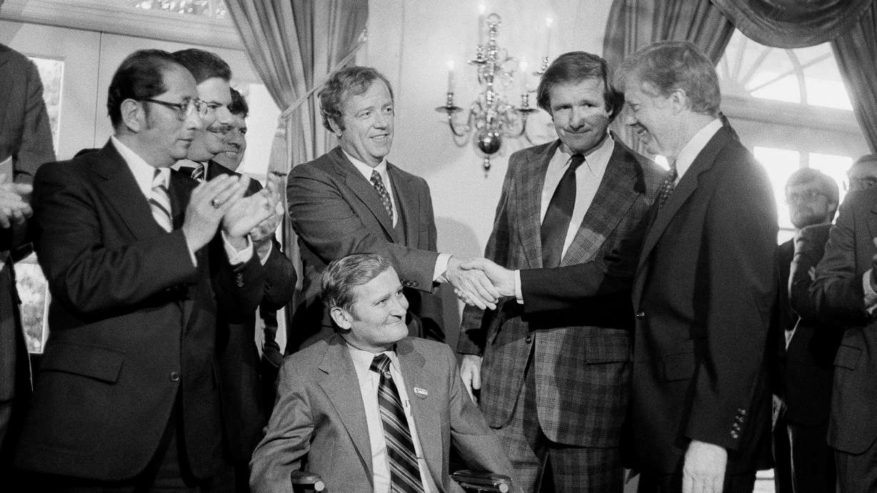 President Jimmy Carter, right, shakes hands with the Michigan delegation, in Washington, April 24, 1980, who were present for the signing by Carter of a bill that would enable Volkswagen to operate an auto assembly plant in a Detroit suburb. Sen. Don Riegle, D-Mich., next to Carter, and Michigan Senate Majority Leader William Faust seated center, look on.