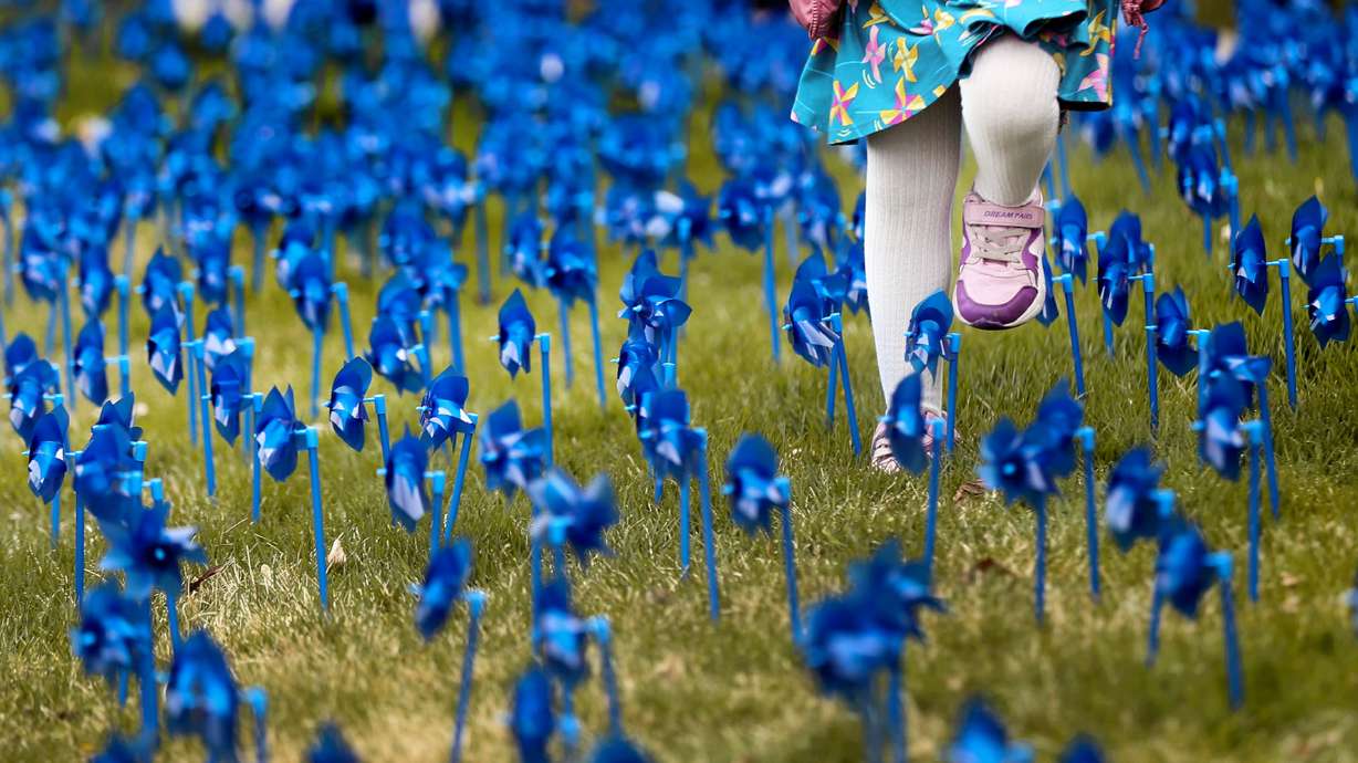 A child walks through a field of blue pinwheels that were planted in honor of every child who was abused in Salt Lake County during 2020 at the Salt Lake County Government Center in Salt Lake City on April 21, 2021.