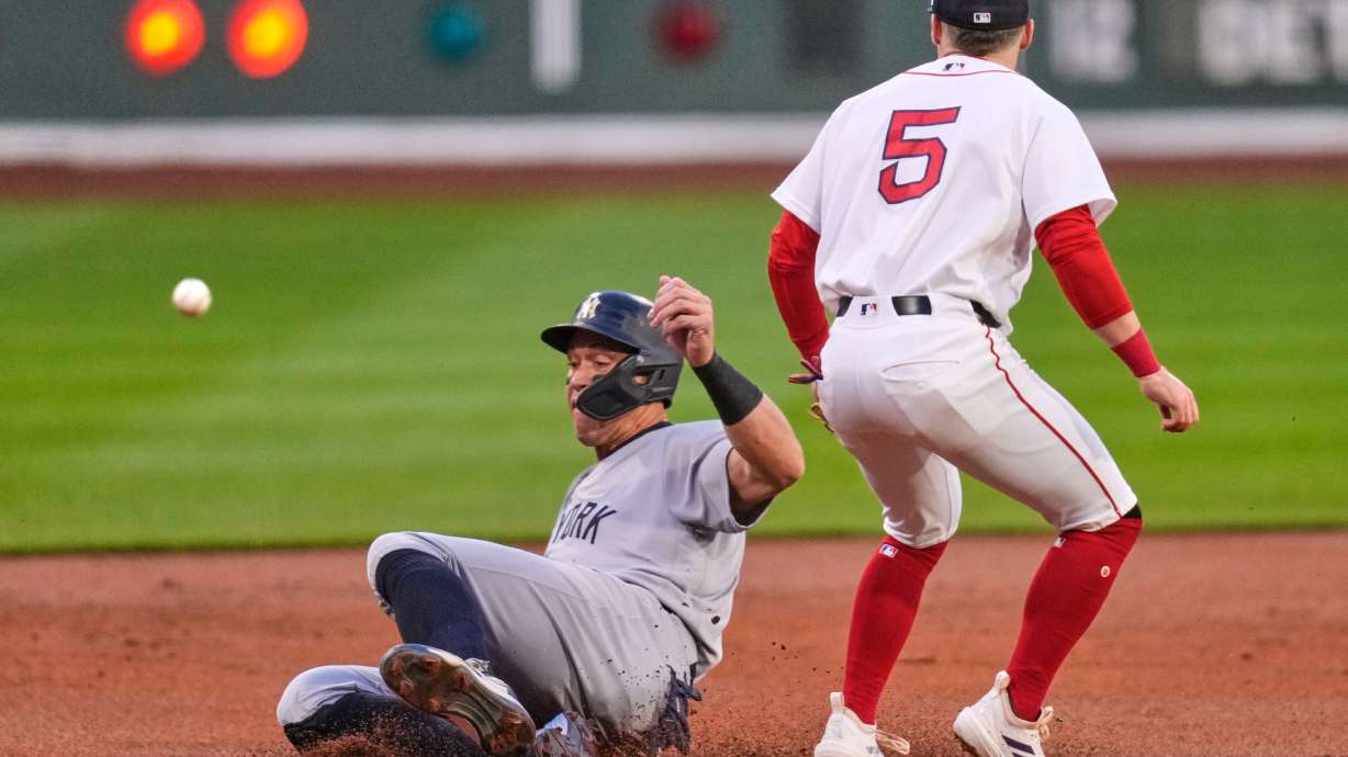 New York Yankees' Aaron Judge, left, beats the throw to Boston Red Sox third baseman Caleb Durbin (5) while advancing on a double by Giancarlo Stanton during the first inning during of a baseball game at Fenway Park, Wednesday, April 22, 2026, in Boston.