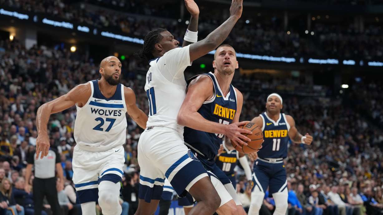 Denver Nuggets center Nikola Jokic, front right, drives the lane as Minnesota Timberwolves centers Naz Reid, center left, and Rudy Gobert, left, defend in the first half in Game 5 of a first-round NBA playoffs basketball series Monday, April 27, 2026, in Denver.