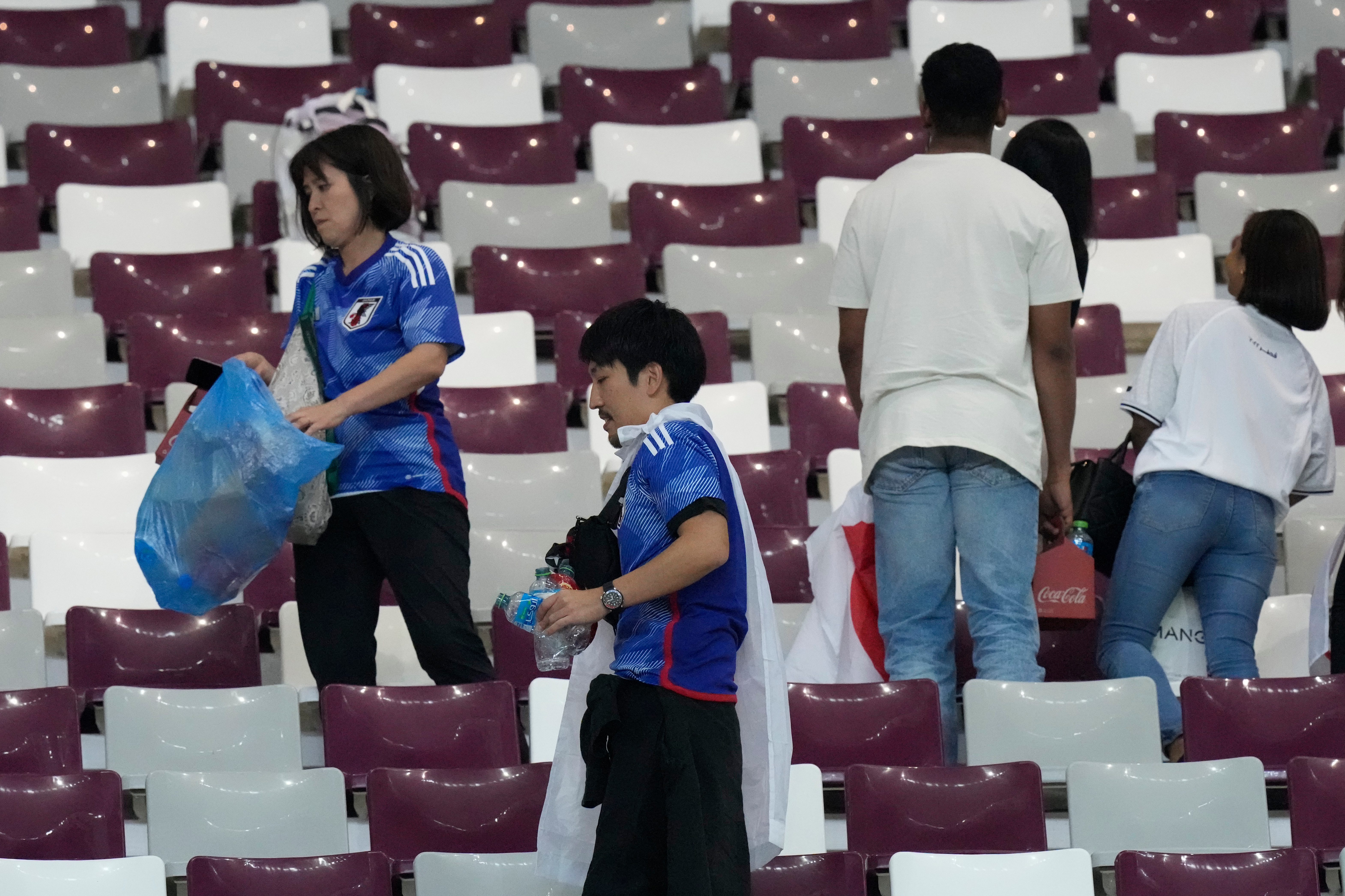 FILE - Japan supporters clean the stands at the end of the World Cup group E soccer match between Germany and Japan, at the Khalifa International Stadium in Doha, Qatar, Wednesday, Nov. 23, 2022. 