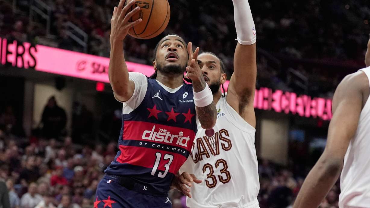 Washington Wizards guard Sharife Cooper (13) goes to the basket past Cleveland Cavaliers forward Olivier Sarr (33) in the second half of an NBA basketball game in Cleveland, Sunday, April 12, 2026.
