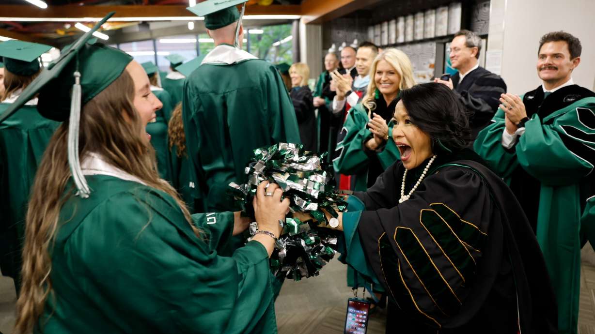Outgoing Utah Valley University President Astrid Tuminez celebrates with a graduate Wednesday at the spring graduation held at the UCCU Center in Orem.