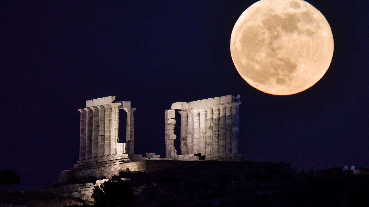 A full flower moon rises behind the Temple of Poseidon at Cape Sounion, Greece, in May 2021. Sky-gazers will be in for a treat this month with two full moons gracing the sky.