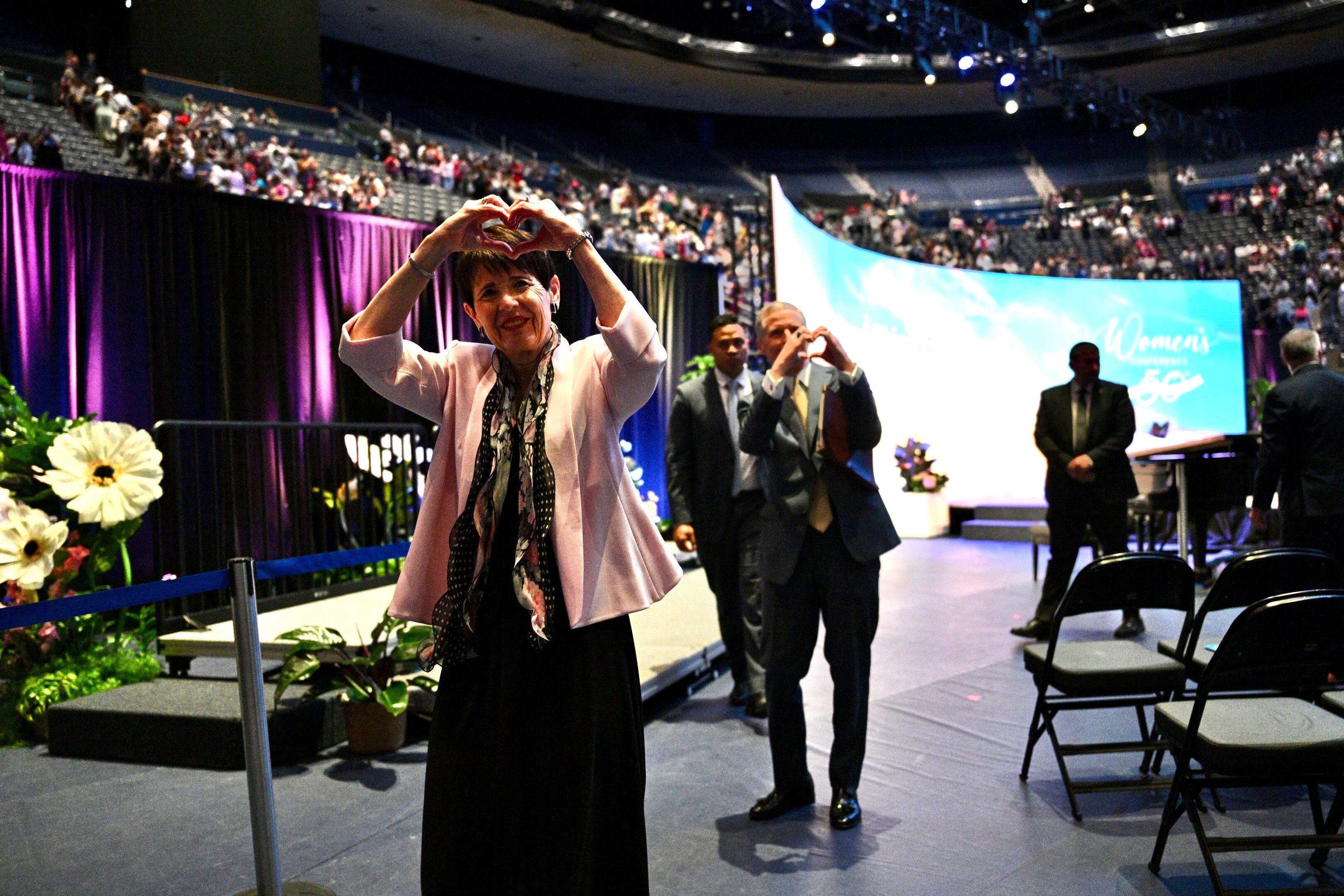 Sister Susan Bednar and Elder David A. Bednar make a heart sign to attendees of BYU Women's Conference, in the Marriott Center in Provo on Friday. The Bednars spoke about their experience ministering to victims of the Michigan meetinghouse attack.