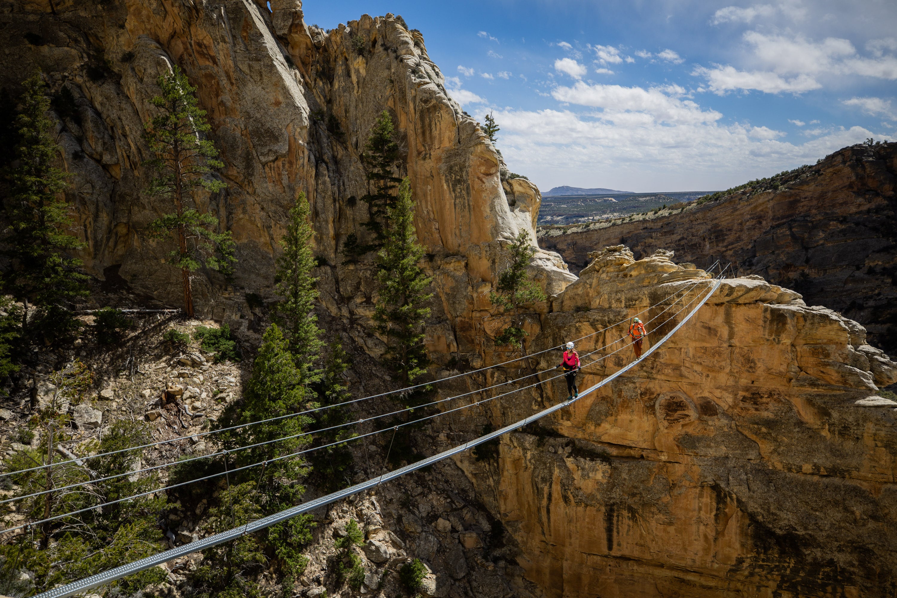 Carolyn Jane Norris, from Vernal, left, and Amber Toler, guide and owner of Dyno Outfitters, right, walk across a sky bridge while climbing the Ashley Gorge Via Ferrata, Utah's first public via ferrata and the longest in the United States, offering a "hard-iron" climbing experience with steel rungs, cables and bridges, in Vernal on April 22.