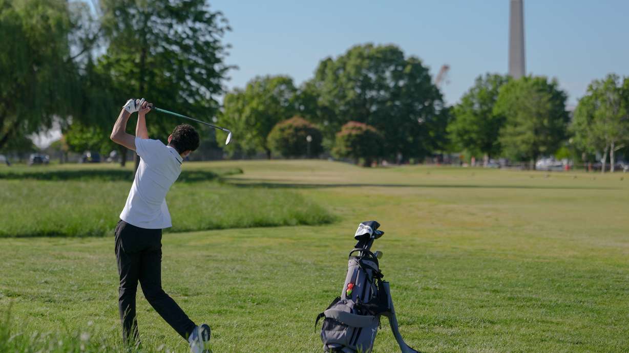 The Washington Monument stands in the background as Roman Sandoli swings at the East Potomac Golf Course, Sunday, May 3, 2026, in Washington.